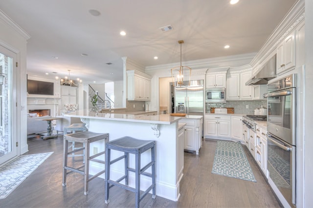 kitchen with open floor plan, built in appliances, a peninsula, light countertops, and white cabinetry