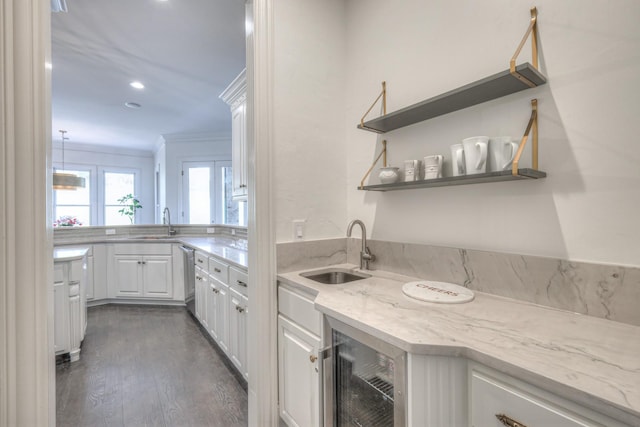 kitchen with white cabinets, light stone counters, ornamental molding, open shelves, and a sink