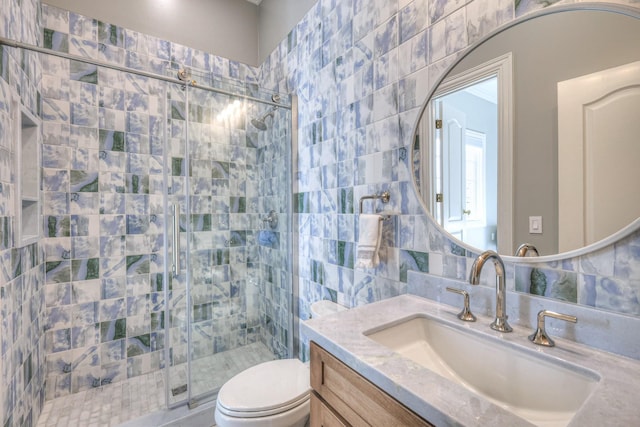 full bath featuring toilet, vanity, tile walls, backsplash, and a stall shower