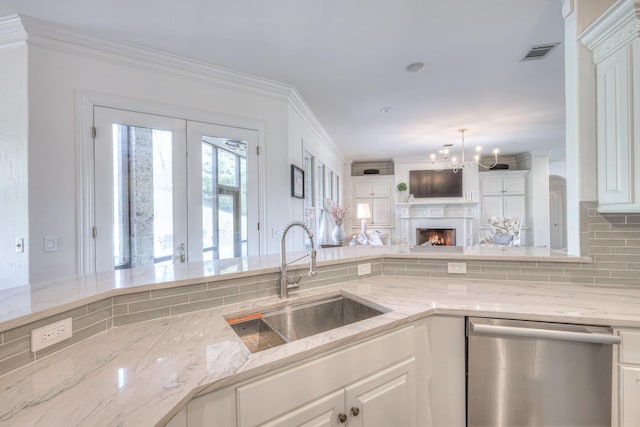 kitchen with a sink, light stone counters, white cabinets, and stainless steel dishwasher