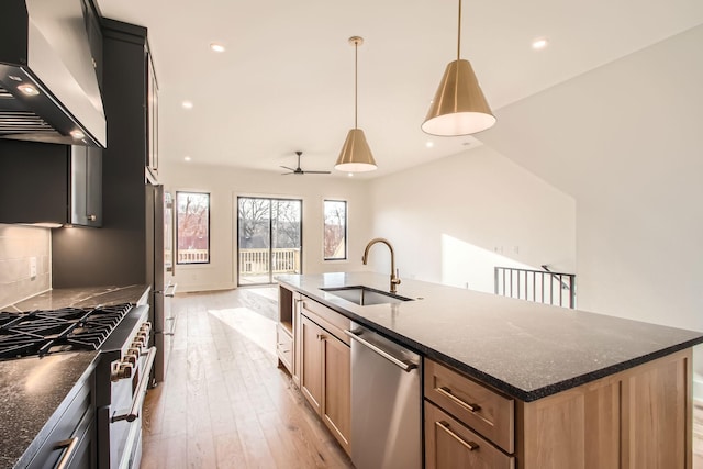 605A Morrow Rd, Nashville, TN 37209 - kitchen featuring an island with sink, hanging light fixtures, stainless steel appliances, wall chimney range hood, and a sink
