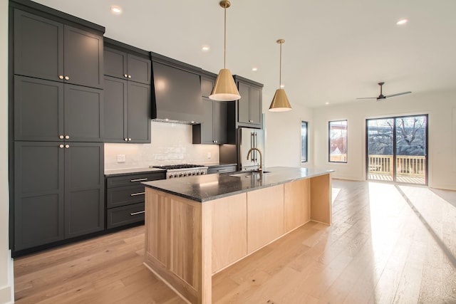 605A Morrow Rd, Nashville, TN 37209 - kitchen with decorative light fixtures, wall chimney exhaust hood, light wood-style flooring, a kitchen island with sink, and high end refrigerator