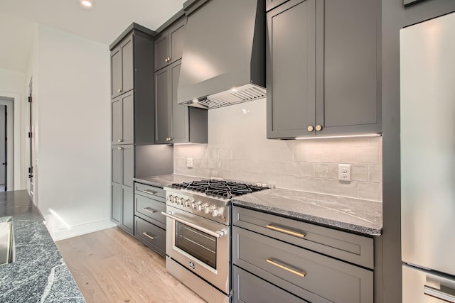 605A Morrow Rd, Nashville, TN 37209 - kitchen featuring wall chimney exhaust hood, high end range, dark stone countertops, freestanding refrigerator, and gray cabinetry