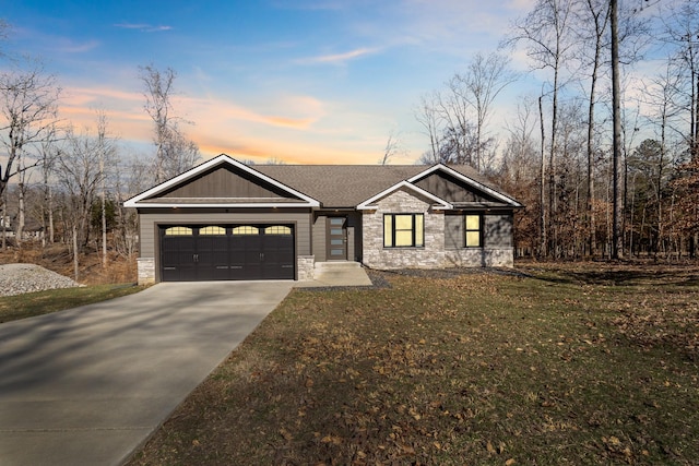 view of front of property featuring stone siding, driveway, a front lawn, and an attached garage