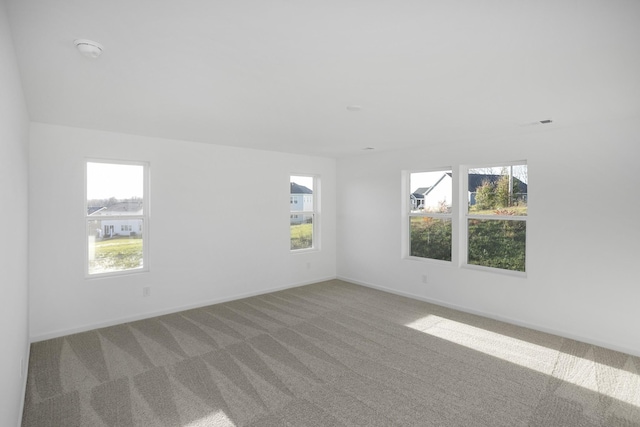 unfurnished room with baseboards, carpet floors, and a healthy amount of sunlight