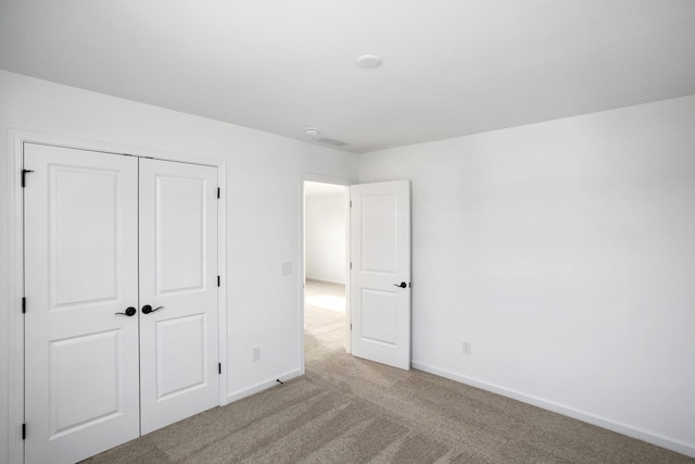 unfurnished bedroom featuring a closet, light colored carpet, and baseboards