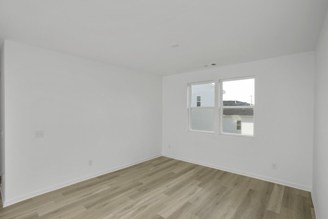 unfurnished room featuring light wood-style flooring, visible vents, and baseboards