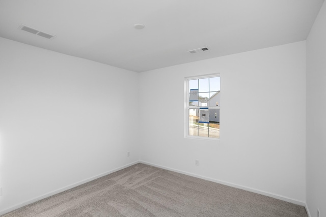 empty room with carpet, visible vents, and baseboards