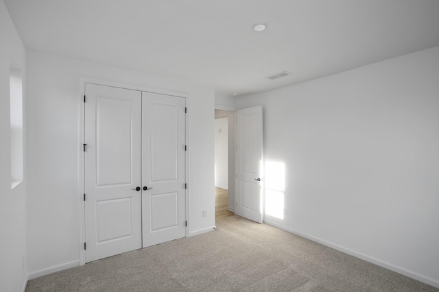 unfurnished bedroom featuring baseboards, a closet, visible vents, and light colored carpet