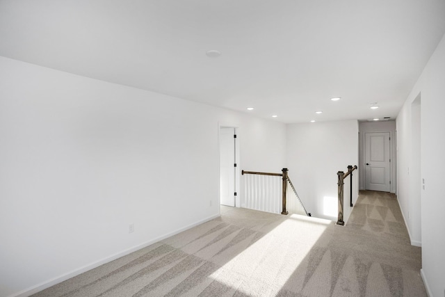 spare room featuring recessed lighting, light colored carpet, and baseboards