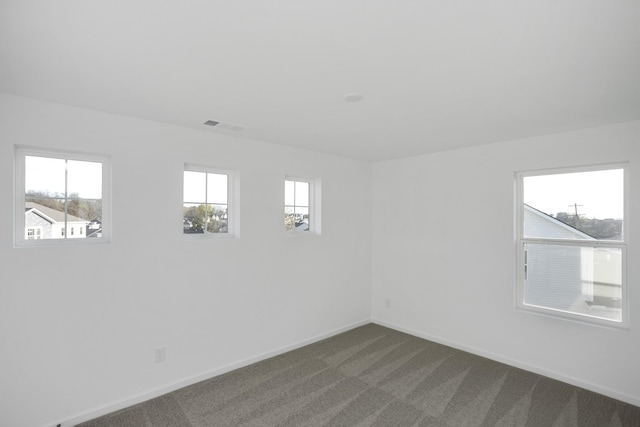 unfurnished room featuring carpet flooring, visible vents, and baseboards