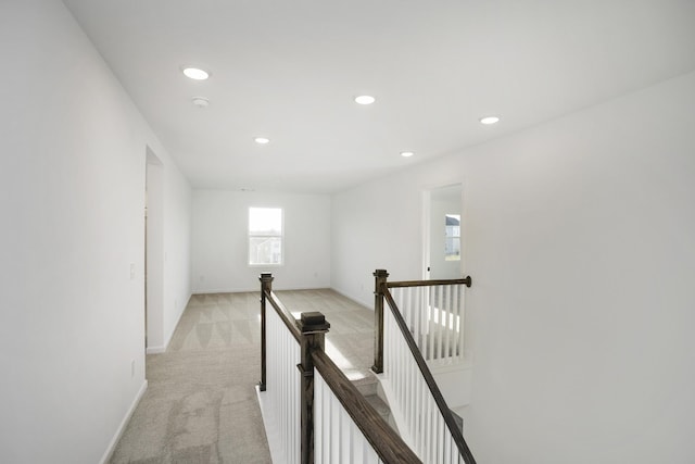 corridor with recessed lighting, baseboards, light colored carpet, and an upstairs landing