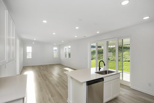 kitchen with a sink, white cabinetry, light countertops, stainless steel dishwasher, and a center island with sink