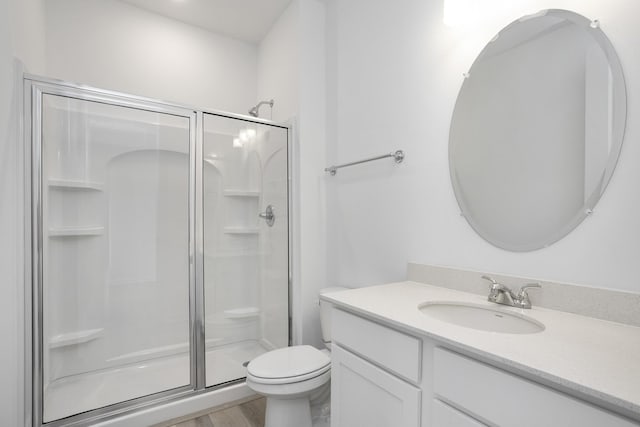 bathroom featuring toilet, a stall shower, wood finished floors, and vanity