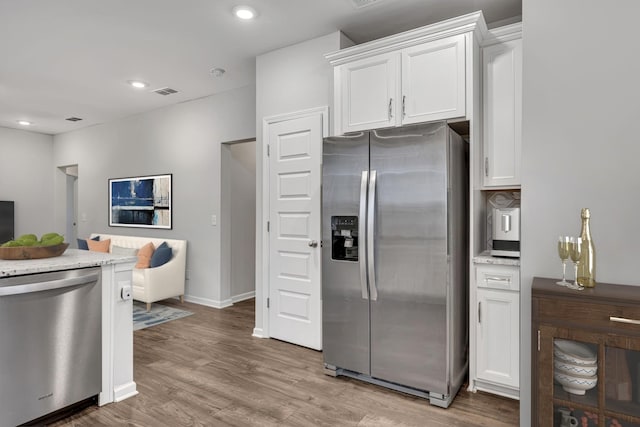 kitchen with appliances with stainless steel finishes, light wood-type flooring, and white cabinets