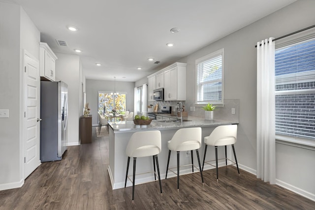 kitchen featuring a peninsula, appliances with stainless steel finishes, visible vents, and white cabinets