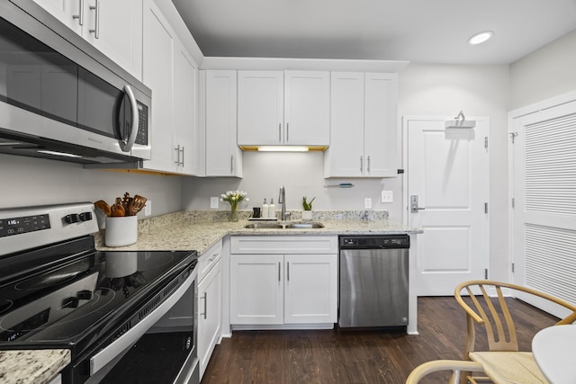 kitchen featuring appliances with stainless steel finishes, a sink, light stone countertops, and white cabinets