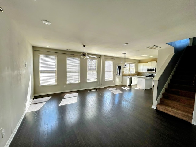 unfurnished living room featuring dark wood-style floors, stairway, visible vents, and baseboards