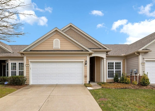 view of front of property with a front yard, roof with shingles, driveway, and an attached garage