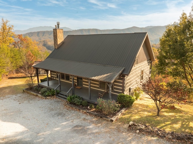 view of front of home featuring metal roof, a porch, a chimney, and a mountain view