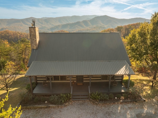 exterior space with a chimney, a mountain view, and metal roof