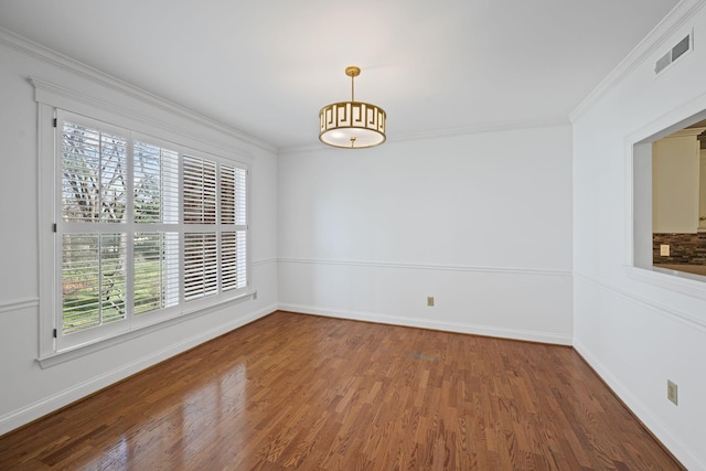 spare room with visible vents, crown molding, baseboards, and wood finished floors