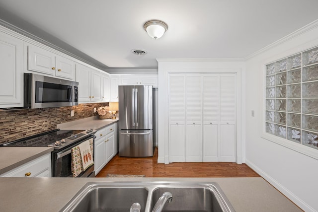 kitchen with visible vents, white cabinets, backsplash, stainless steel appliances, and a sink