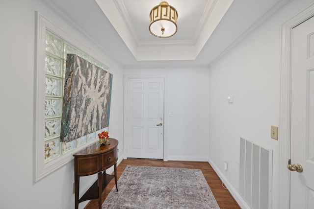 foyer featuring baseboards, visible vents, a raised ceiling, dark wood-style flooring, and crown molding