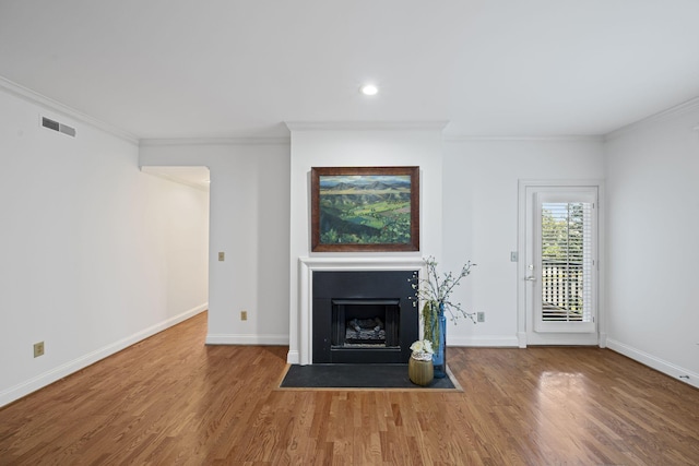 unfurnished living room featuring wood finished floors, a fireplace with flush hearth, visible vents, and baseboards