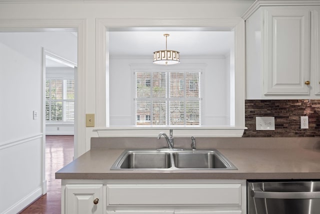 kitchen featuring ornamental molding, white cabinets, a sink, and dishwasher