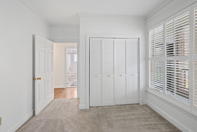 unfurnished bedroom with baseboards, crown molding, and light colored carpet