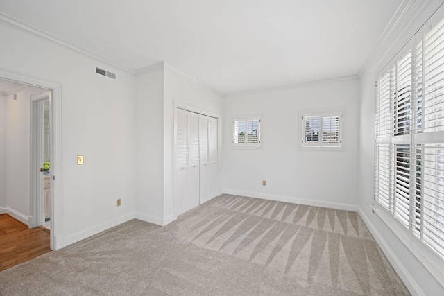 unfurnished bedroom featuring light carpet, visible vents, baseboards, and crown molding