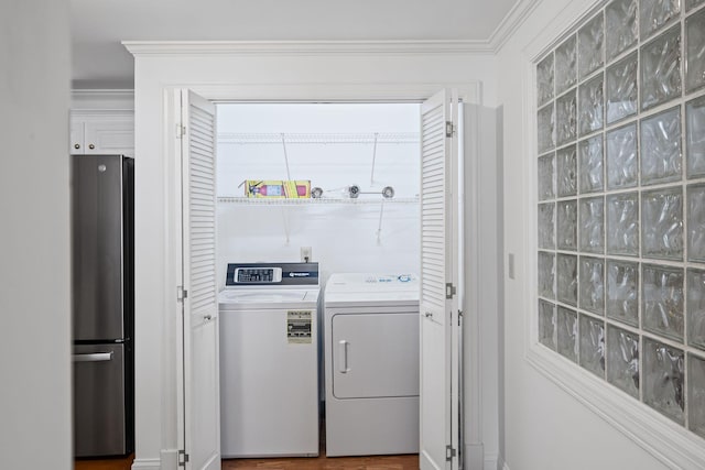 clothes washing area featuring laundry area, ornamental molding, and washer and clothes dryer