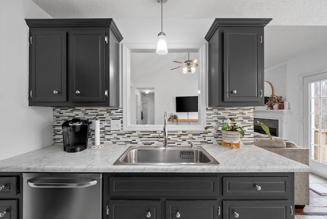 kitchen with dark cabinets, light countertops, a sink, and stainless steel dishwasher