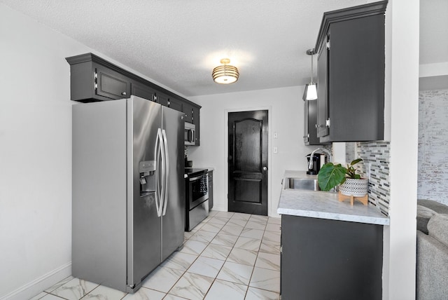 kitchen with dark cabinets, marble finish floor, stainless steel appliances, light countertops, and a sink