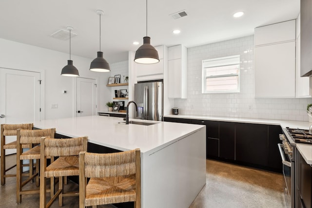 kitchen featuring a kitchen island with sink, a sink, visible vents, light countertops, and appliances with stainless steel finishes