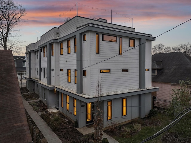 back of house at dusk featuring fence