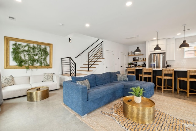 living room featuring finished concrete flooring, stairs, visible vents, and recessed lighting