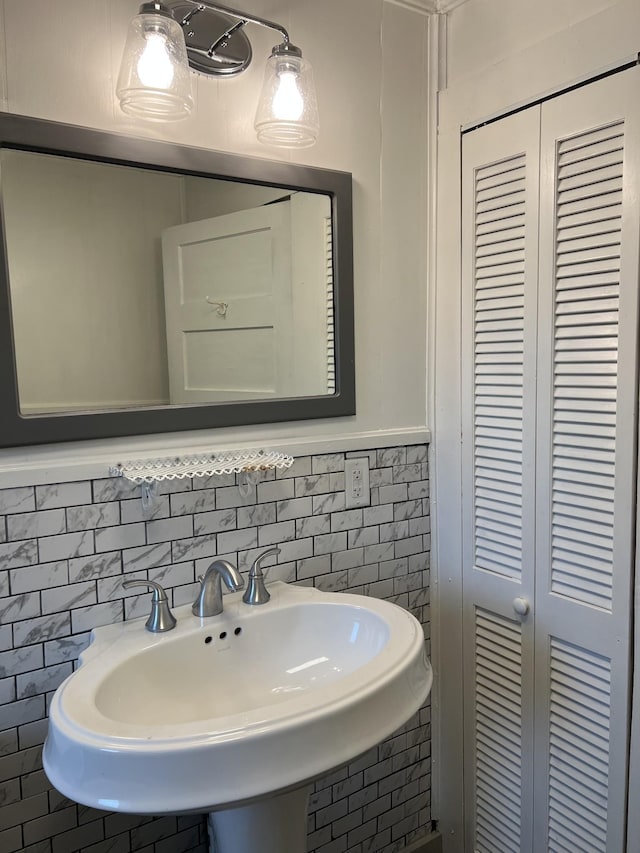 bathroom featuring wainscoting, a sink, and tile walls