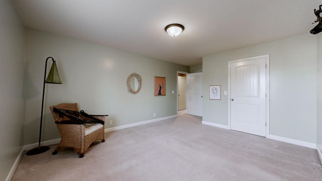 living area featuring baseboards and light colored carpet