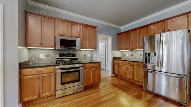 kitchen featuring brown cabinets, light wood-style floors, dark stone counters, and stainless steel appliances