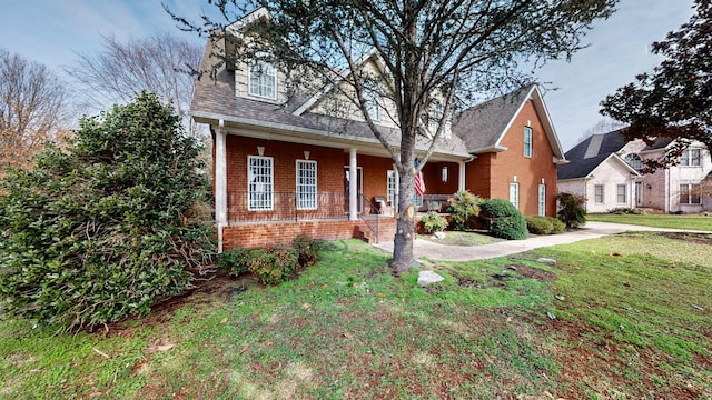 view of front of house featuring covered porch, a front lawn, and brick siding