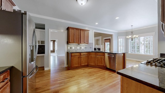 kitchen with hanging light fixtures, brown cabinets, stainless steel appliances, and a sink