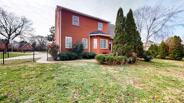 view of front facade featuring fence, a front lawn, and brick siding