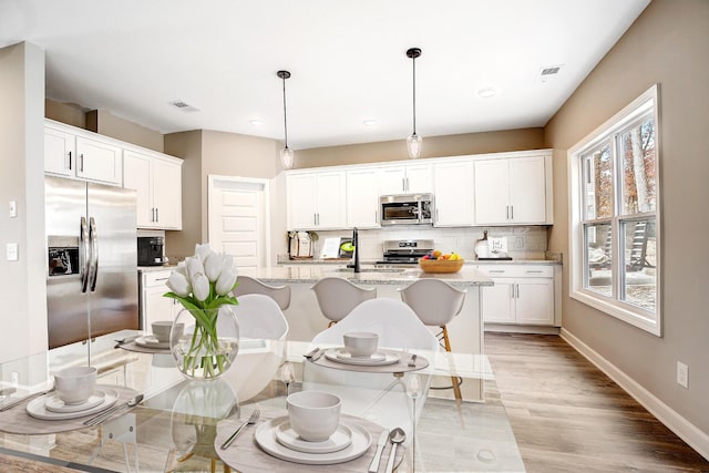 dining space featuring light wood finished floors, visible vents, and baseboards