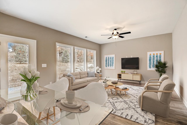 living area with visible vents, ceiling fan, baseboards, and wood finished floors