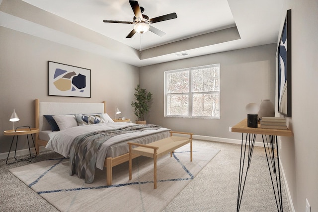 bedroom with ceiling fan, light carpet, visible vents, baseboards, and a tray ceiling