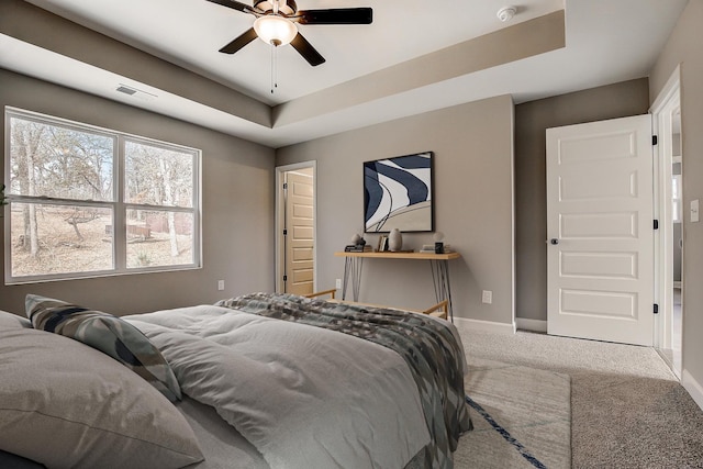 bedroom featuring a tray ceiling, baseboards, visible vents, and carpet flooring