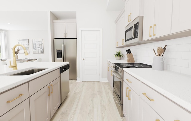 kitchen featuring a sink, stainless steel appliances, light countertops, white cabinetry, and backsplash