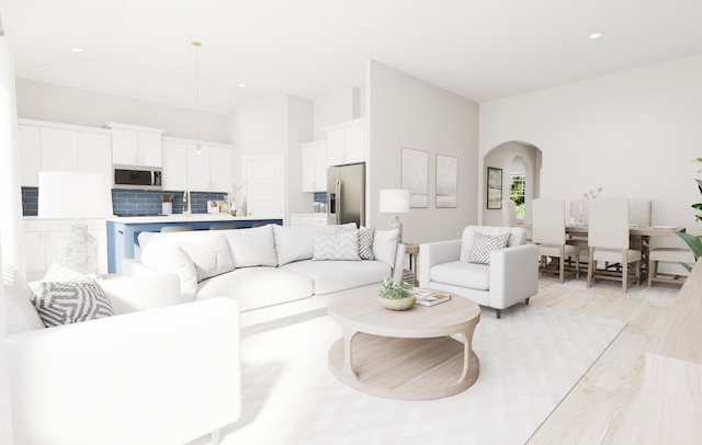 living area with light wood-type flooring, arched walkways, and recessed lighting